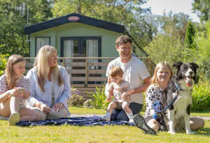 Holiday homeowners at Newby Bridge Country Caravan Park sitting outside on the grass in front of a holiday home.